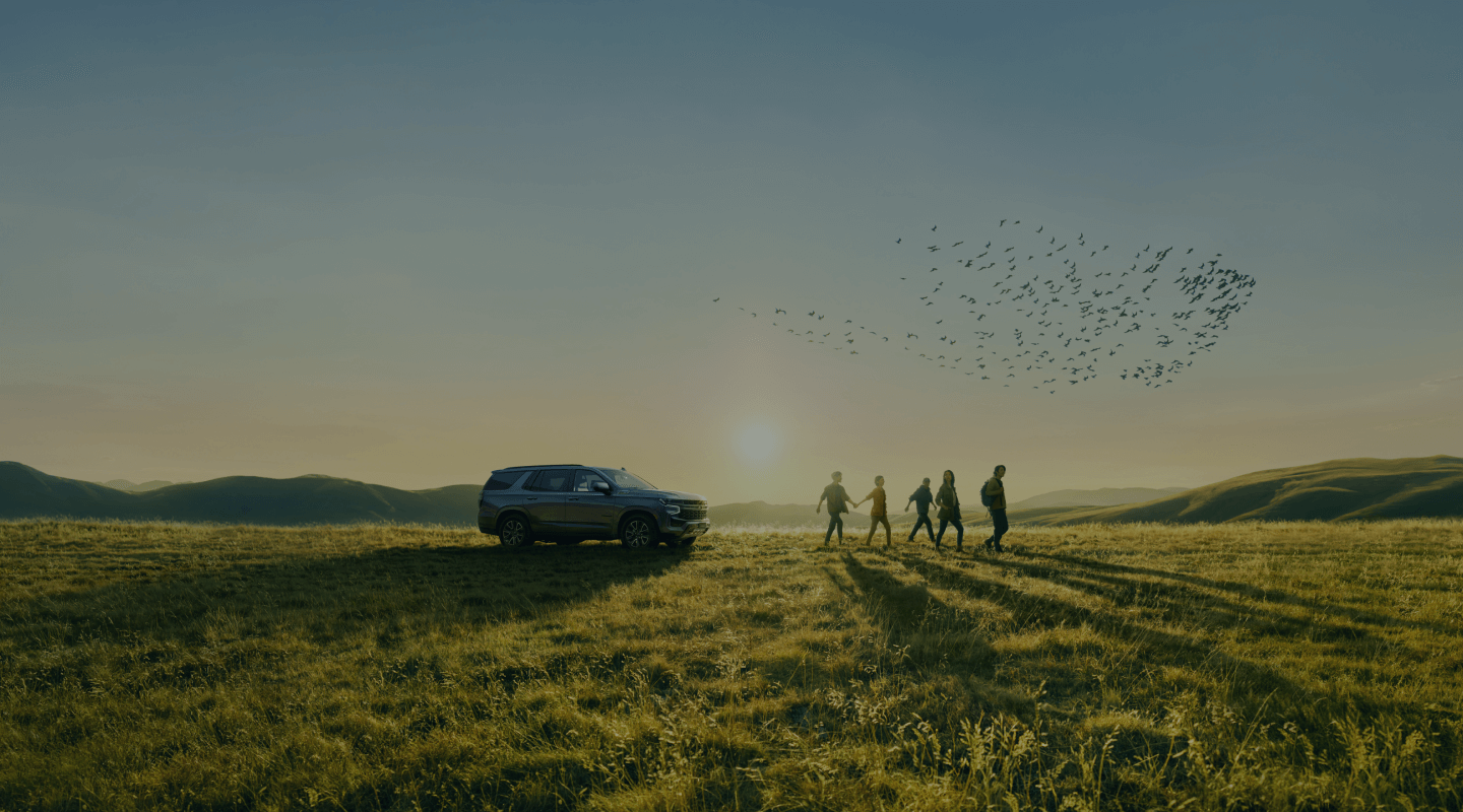 Chevrolet Tahoe parked in a field with a group of people walking away from it