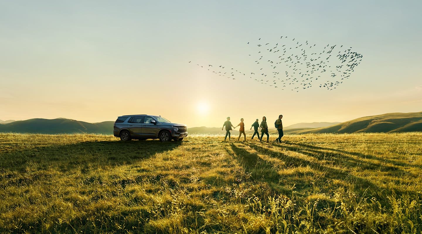 Chevrolet Tahoe parked in a field with a group of people walking away from it